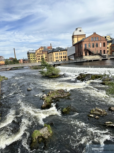 Small waterfall with industrial buildings in the background